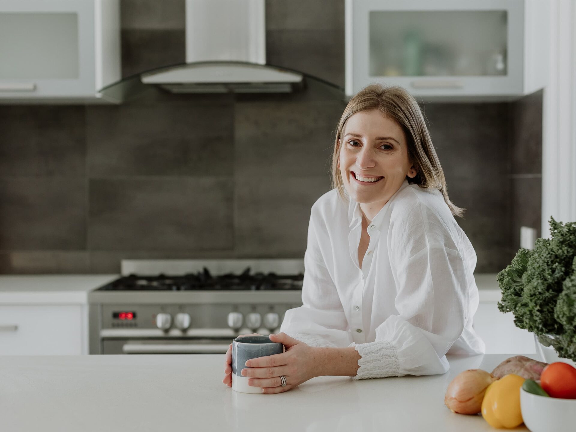 Kendall smiling in the kitchen holding a mug