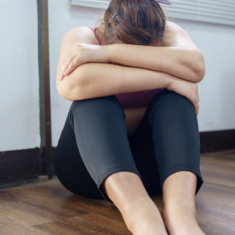 Woman with head in arms sitting on floor