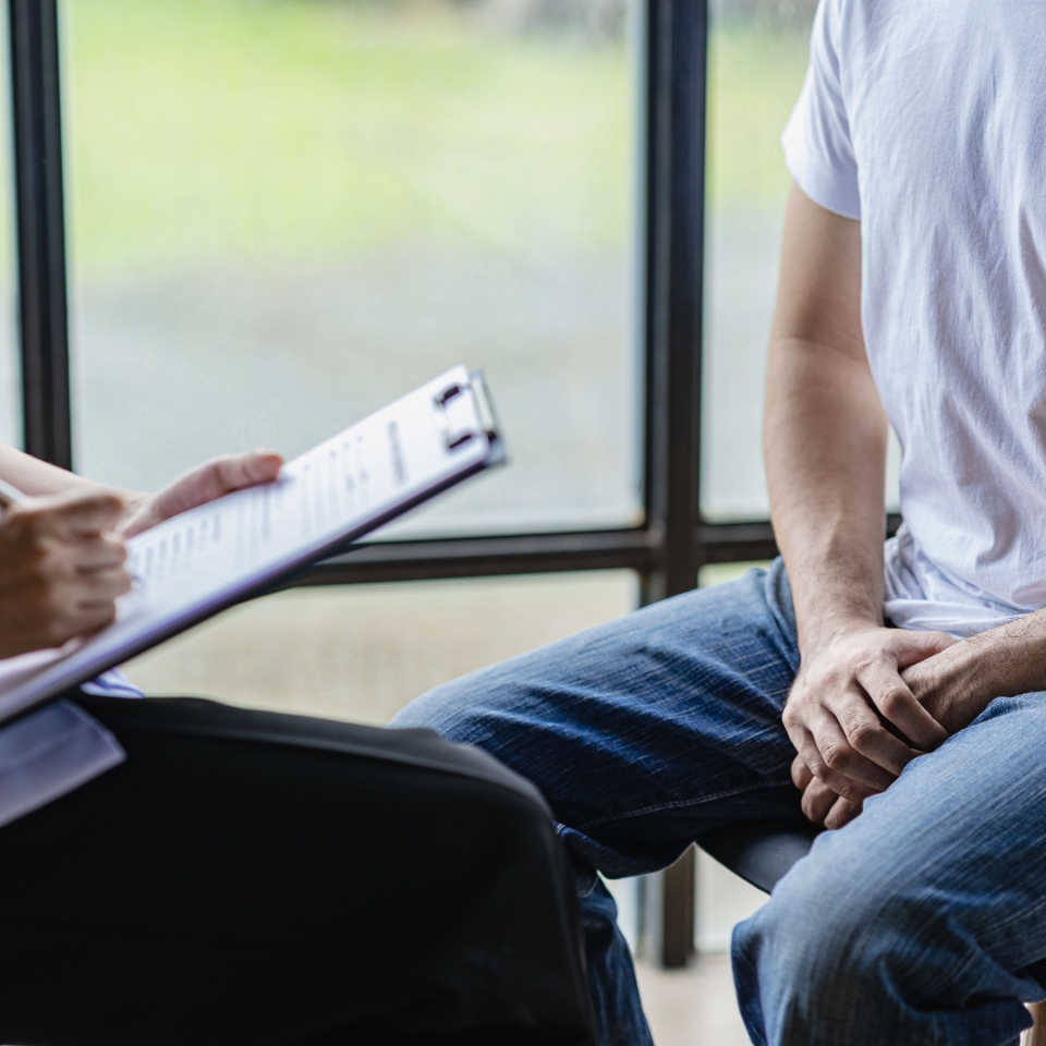 Man with hands in lap at health appointment woman